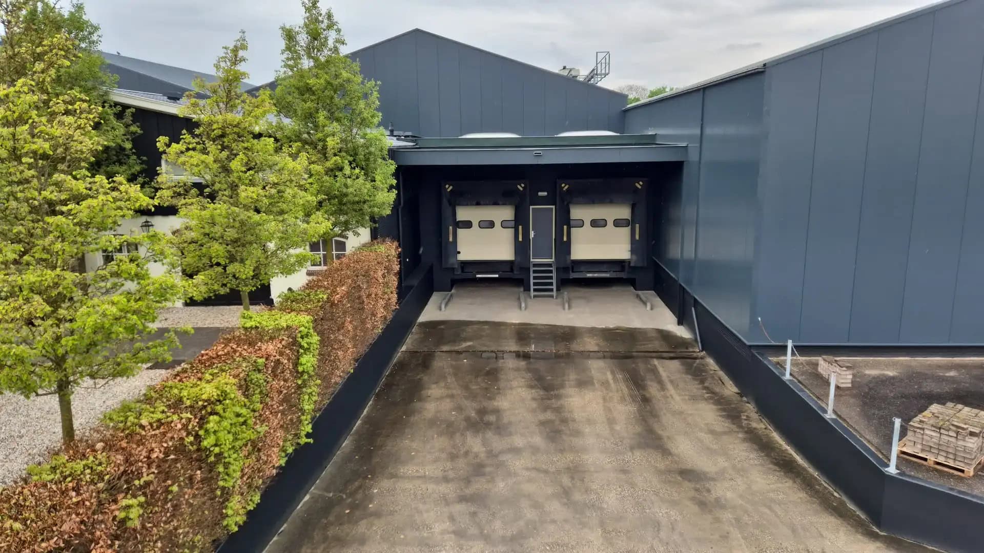 Moderne bedrijfsgebouw met laadperron en groene omgeving.